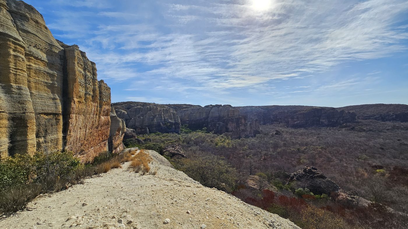 Overlook along a canyon-rim trail, sandstone cliff on one side, wide valley below